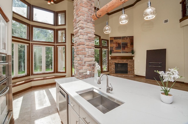 kitchen featuring a towering ceiling, stainless steel dishwasher, a sink, and visible vents