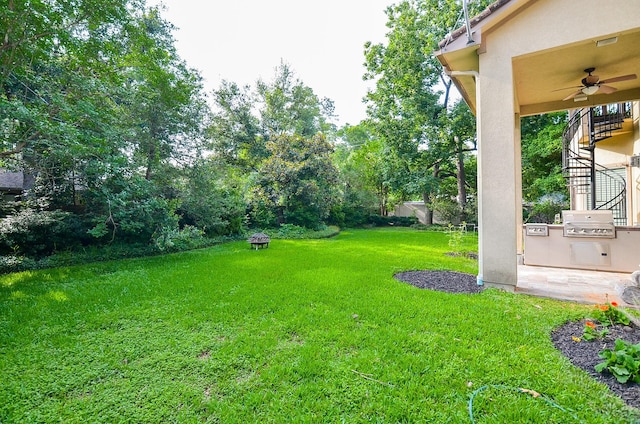 view of yard featuring exterior kitchen, ceiling fan, and stairway