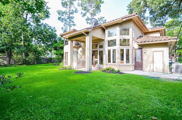 rear view of property with a tiled roof, fence, cooling unit, a yard, and stucco siding