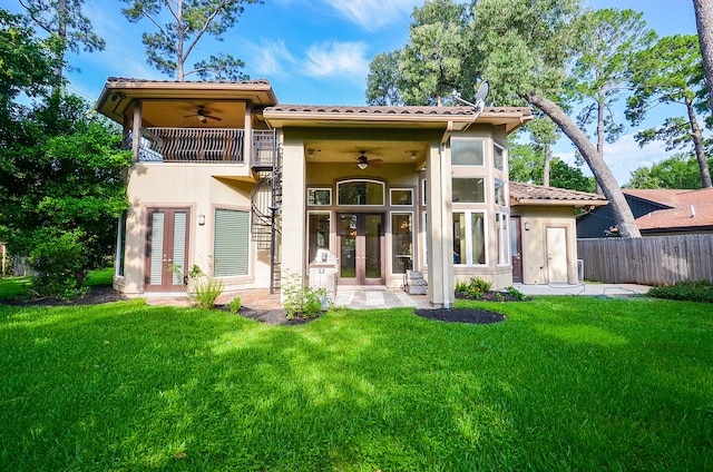 back of property featuring a balcony, ceiling fan, and a yard