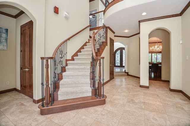 entryway with arched walkways, baseboards, stairs, and crown molding