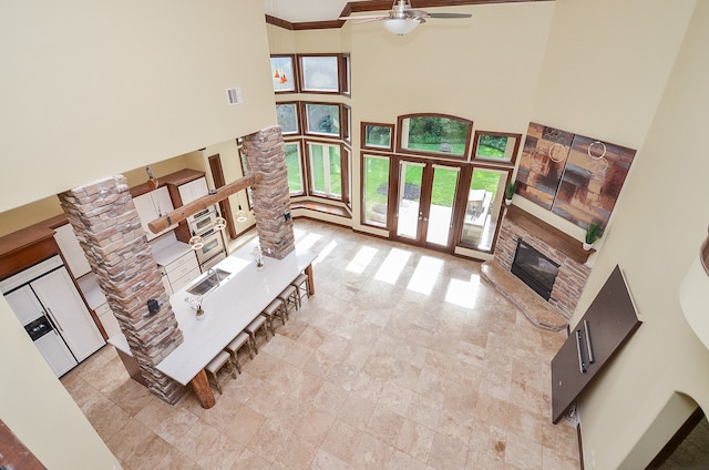 living room with ceiling fan, a high ceiling, ornamental molding, sink, and light tile patterned flooring