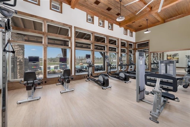 workout area with light wood-type flooring, wood ceiling, and a high ceiling