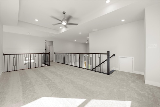 spare room featuring ceiling fan, a raised ceiling, and light colored carpet