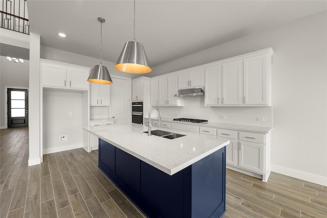 kitchen with decorative light fixtures, sink, white cabinetry, and an island with sink