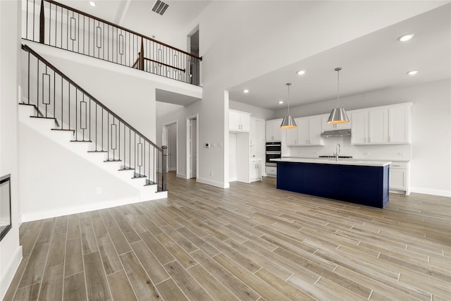 kitchen with sink, a center island with sink, white cabinets, and light hardwood / wood-style flooring