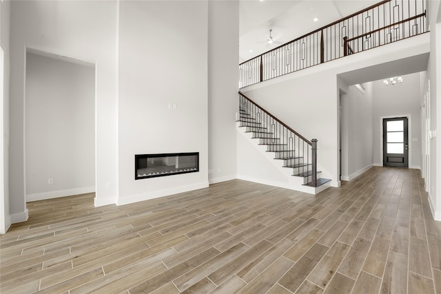 unfurnished living room with light wood-type flooring and a high ceiling