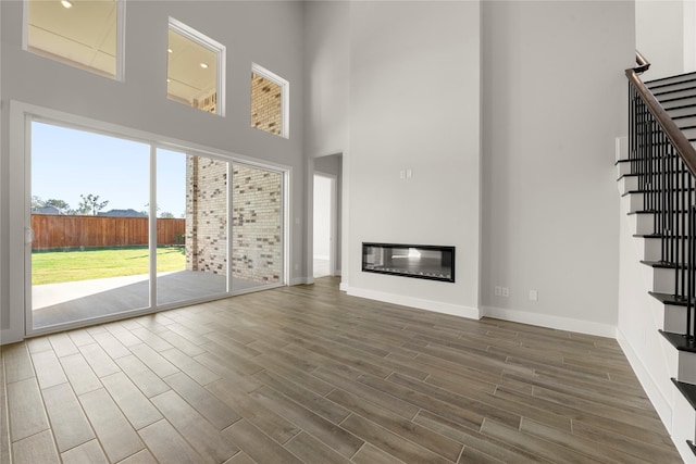 unfurnished living room featuring dark wood-type flooring and a high ceiling