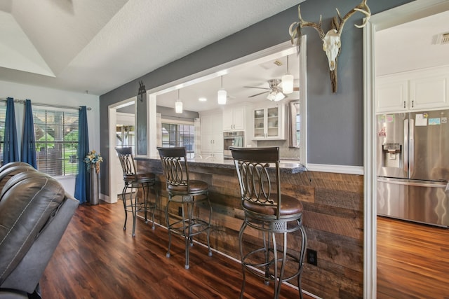 dining space with a wealth of natural light, dark wood-type flooring, and ceiling fan