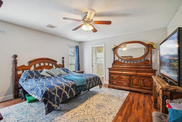 bedroom featuring ceiling fan, dark hardwood / wood-style flooring, a textured ceiling, and ensuite bath