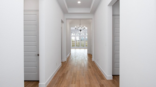 hall featuring an inviting chandelier and light hardwood / wood-style floors