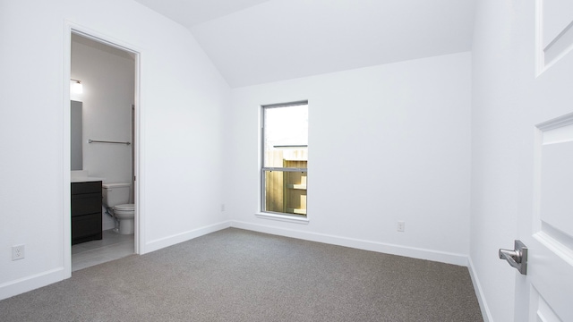 unfurnished bedroom featuring carpet, ensuite bath, and lofted ceiling