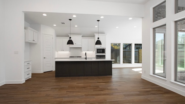 kitchen with stainless steel appliances, white cabinetry, sink, dark hardwood / wood-style floors, and a kitchen island with sink