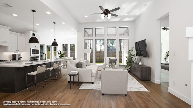 living room featuring a towering ceiling, dark hardwood / wood-style flooring, ceiling fan, and sink