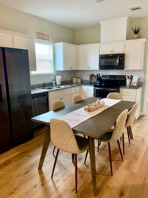 kitchen with backsplash, light hardwood / wood-style flooring, sink, black appliances, and white cabinets