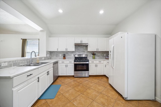 kitchen with lofted ceiling, sink, white cabinets, backsplash, and stainless steel appliances