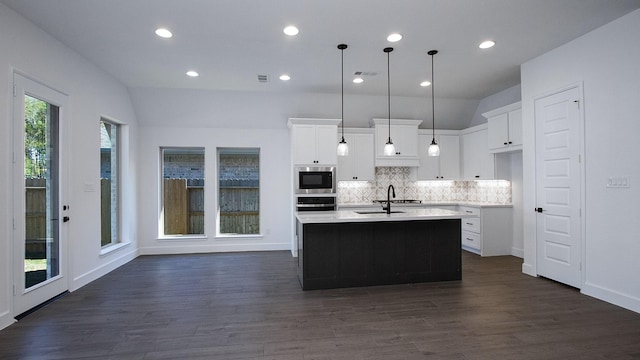 17711 Monarch Vista Ln, Conroe, TX 77302 - kitchen featuring appliances with stainless steel finishes, light countertops, decorative backsplash, dark wood finished floors, and white cabinetry