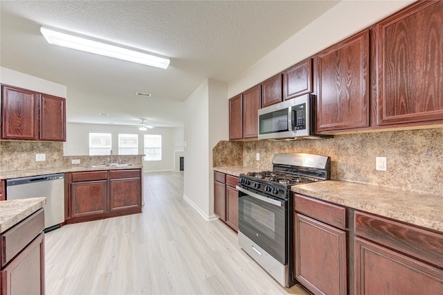 kitchen featuring light hardwood / wood-style flooring, sink, ceiling fan, stainless steel appliances, and tasteful backsplash