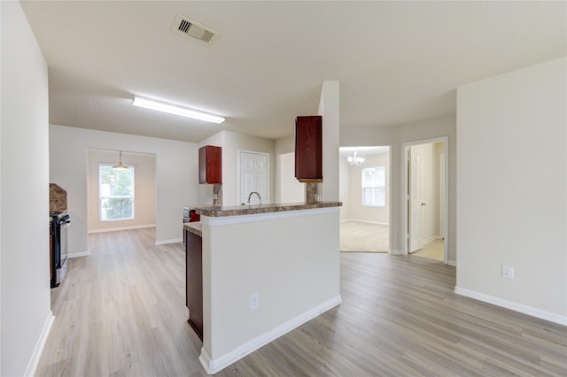 kitchen featuring light hardwood / wood-style floors, a chandelier, and kitchen peninsula