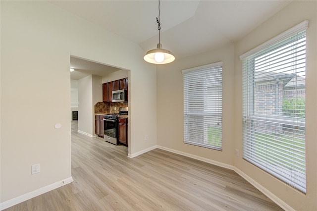 unfurnished dining area featuring light hardwood / wood-style flooring and lofted ceiling