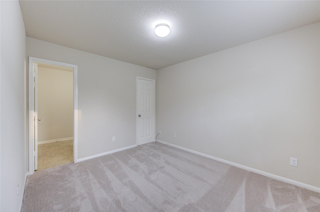 empty room with a textured ceiling and light carpet