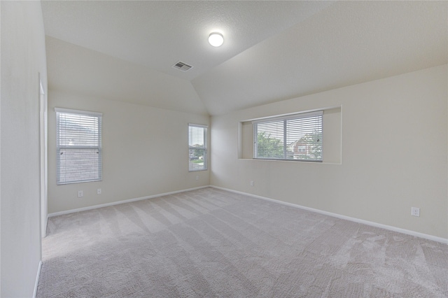 carpeted empty room with lofted ceiling