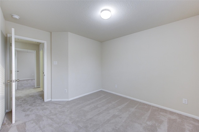 empty room with a textured ceiling and light carpet