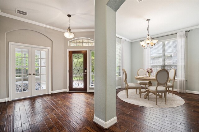 foyer entrance featuring crown molding, dark wood-type flooring, and a notable chandelier