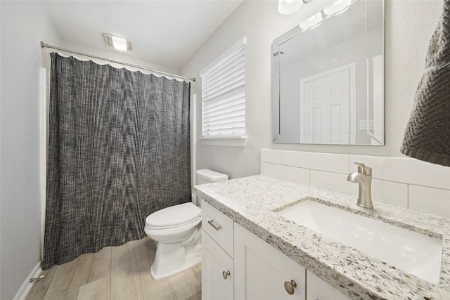 bathroom with hardwood / wood-style floors, backsplash, toilet, and vanity