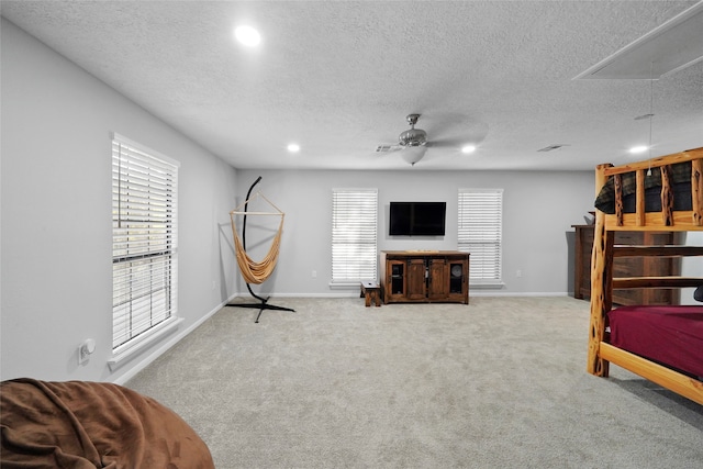 interior space with a textured ceiling, ceiling fan, and light carpet