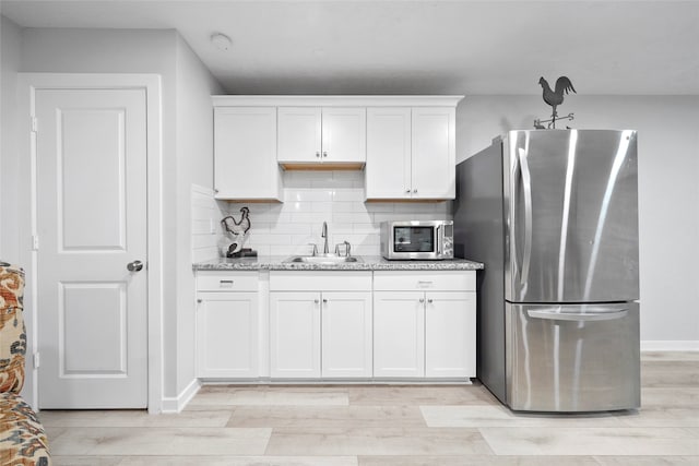 kitchen featuring sink, stainless steel appliances, light hardwood / wood-style flooring, and white cabinets