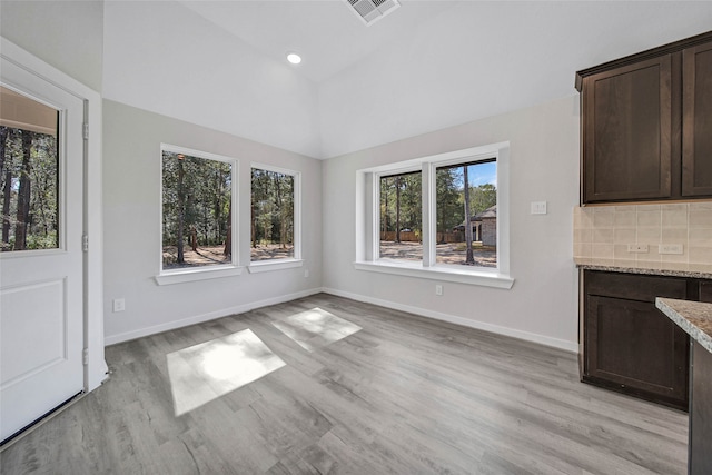 unfurnished dining area with lofted ceiling and light hardwood / wood-style flooring