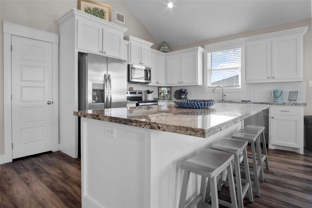 kitchen with dark hardwood / wood-style flooring, white cabinets, appliances with stainless steel finishes, and lofted ceiling