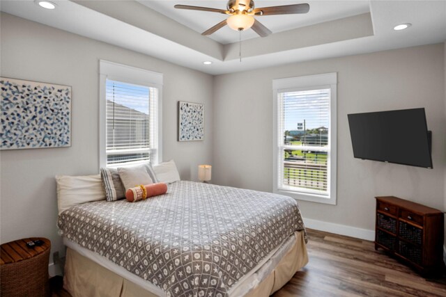 bedroom with ceiling fan, hardwood / wood-style flooring, and a tray ceiling