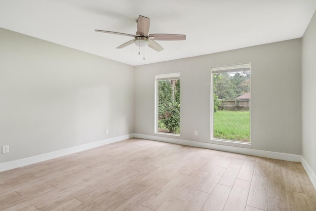 spare room featuring ceiling fan, light wood-style flooring, and baseboards