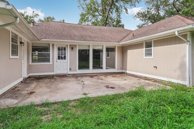 doorway to property featuring a shingled roof and a patio