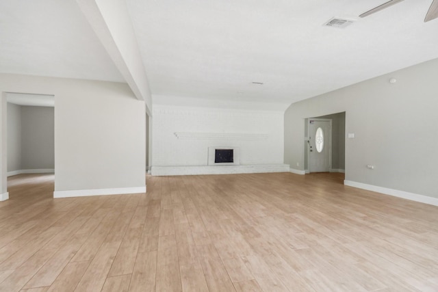 unfurnished living room featuring ceiling fan, a fireplace, visible vents, baseboards, and light wood-style floors