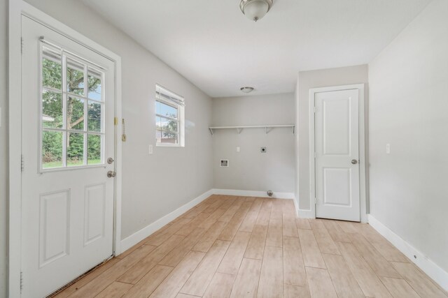 clothes washing area with hookup for an electric dryer, hookup for a washing machine, and light hardwood / wood-style flooring