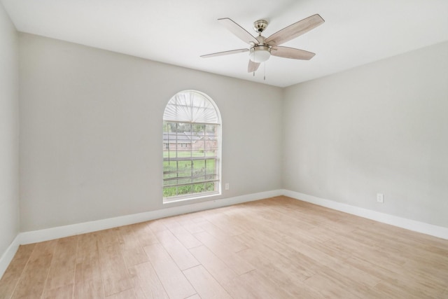 empty room featuring a ceiling fan, light wood-style flooring, and baseboards