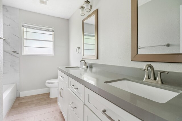 bathroom with wood-type flooring, dual vanity, and toilet