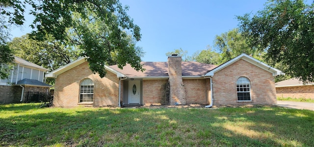 ranch-style home with brick siding, a chimney, and a front lawn