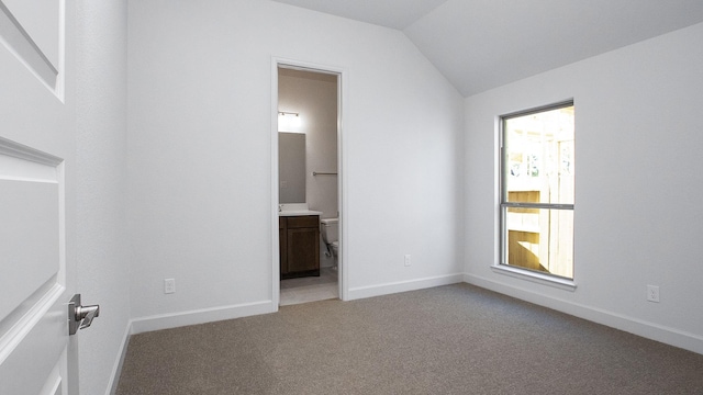 unfurnished bedroom with ensuite bath, lofted ceiling, carpet, and multiple windows