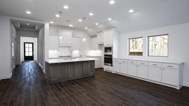 kitchen featuring dark hardwood / wood-style flooring, stainless steel appliances, a large island with sink, white cabinetry, and lofted ceiling