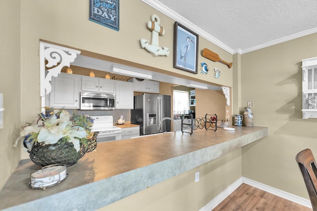 kitchen featuring appliances with stainless steel finishes, tasteful backsplash, a textured ceiling, wood-type flooring, and crown molding