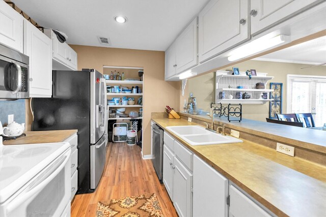 kitchen featuring white cabinets, sink, appliances with stainless steel finishes, crown molding, and light hardwood / wood-style floors