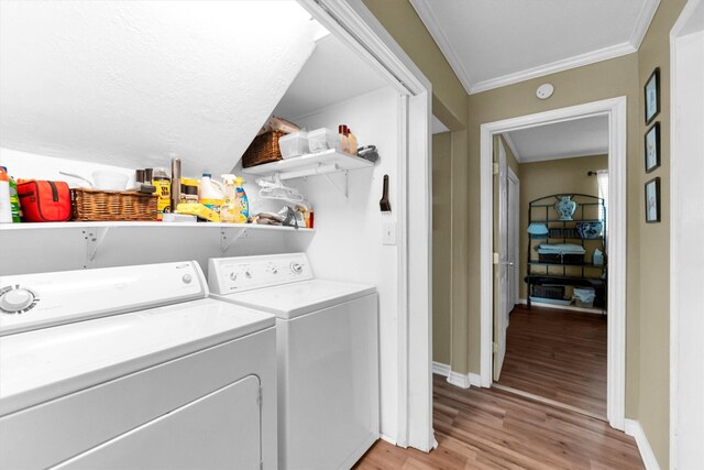 clothes washing area featuring crown molding, separate washer and dryer, and light hardwood / wood-style flooring