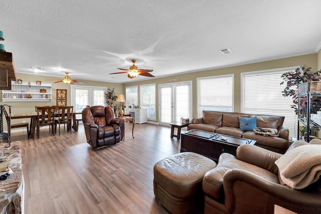 living room with ornamental molding, light wood-type flooring, a textured ceiling, and ceiling fan