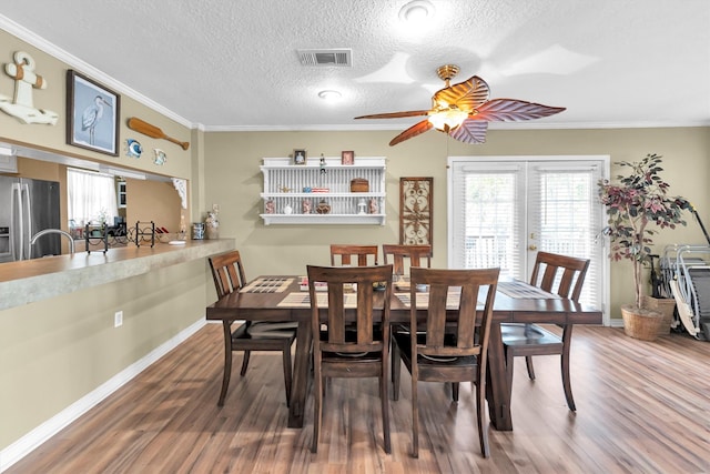 dining area featuring ceiling fan, ornamental molding, a textured ceiling, and hardwood / wood-style floors