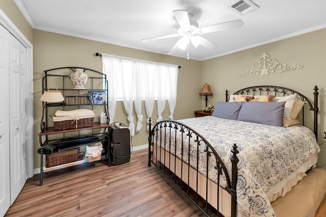 bedroom with wood-type flooring, ornamental molding, ceiling fan, and a closet