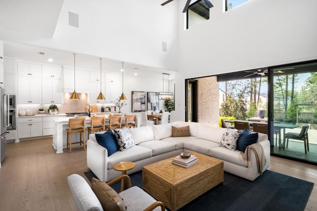 living room with a towering ceiling, hardwood / wood-style flooring, and ceiling fan